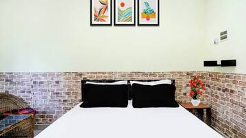 Una habitación de hotel con una pared de ladrillo, una cama con ropa de cama blanco y negro, y tres obras de arte enmarcadas en la pared.