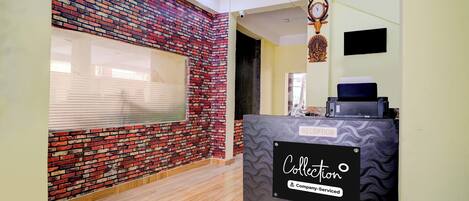 A reception area with a brick wall, a reception desk labeled 'Collection Company-Serviced,' and a clock on the wall.