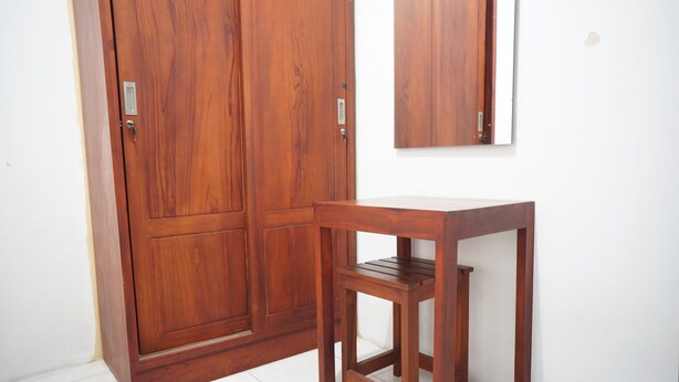 Une armoire en bois avec un miroir au-dessus et une petite table en bois à côté.