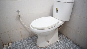 Des toilettes blanches avec un réservoir, un siège-bidet et un porte-rouleau de papier toilette.