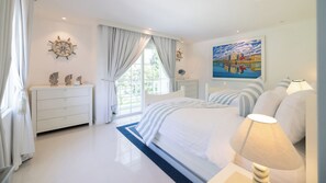 Ein Schlafzimmer mit Bett, Nachttischen, einem Fenster mit Vorhängen, einem Gemälde und einer Lampe.