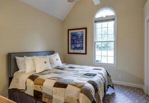Ein Schlafzimmer mit einem großen Bett, einem Deckenventilator, einem Fenster und einem gerahmten Bild an der Wand.