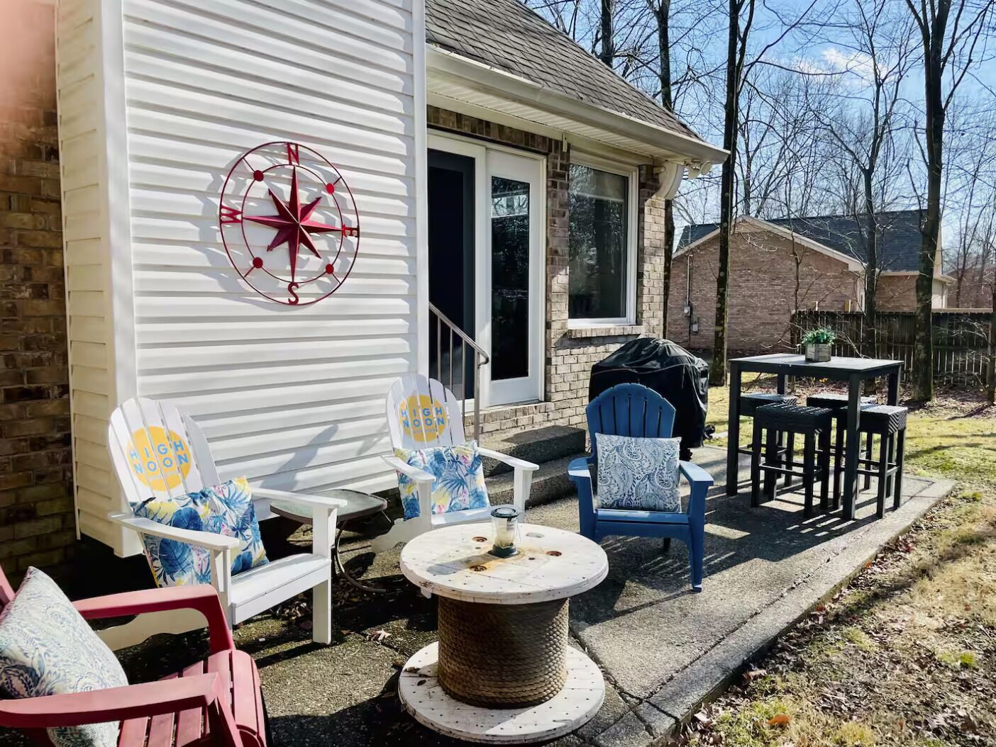 Un patio con mobiliario exterior, una brújula decorativa y una zona de parrilla cubierta.