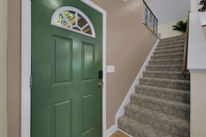 A green door with a window, a carpeted staircase, and a wall with a light switch. - Comfy wooded country house close from Nashville. (Nashville)