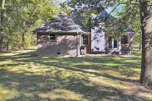 A two-story stone house with a chimney, a porch, and a small garden area. - Comfy wooded country house close from Nashville. (Nashville)