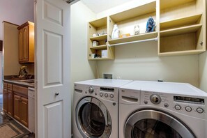 A laundry area with two front-loading washing machines, wooden cabinets, and a shelf with various items. - Comfy wooded country house close from Nashville. (Nashville)