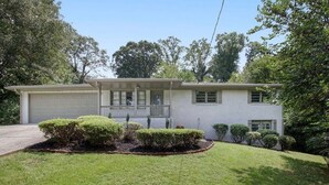 A single-story house with a garage, a front porch, and a well-maintained lawn. - Emerald Retreat - Modern 3 Bedroom Near Atlanta (Austell)