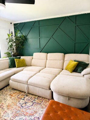 A sectional sofa with a geometric-patterned wall behind it. - Emerald Retreat - Modern 3 Bedroom Near Atlanta (Austell)