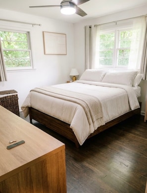 A bedroom with a bed, a bedside table, a lamp, and a ceiling fan. - Emerald Retreat - Modern 3 Bedroom Near Atlanta (Austell)