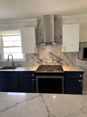 A kitchen with a built-in stove, a sink, and cabinets. - Emerald Retreat - Modern 3 Bedroom Near Atlanta (Austell)