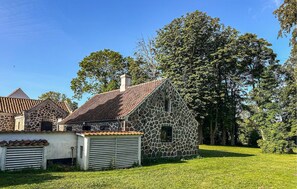 A stone building with a tiled roof, surrounded by grass and trees. - 3 bedroom stunning home in Haarby (Haarby)
