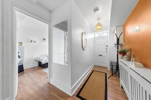 A modern interior with a wooden floor, white walls, a black and brown doormat, and a white radiator. - STUNNING Home in the Heart of Whitechapel - Minutes from Central London (London)