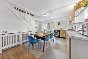 Eine moderne Küche mit Essbereich, einer Waschmaschine und einer Treppe.