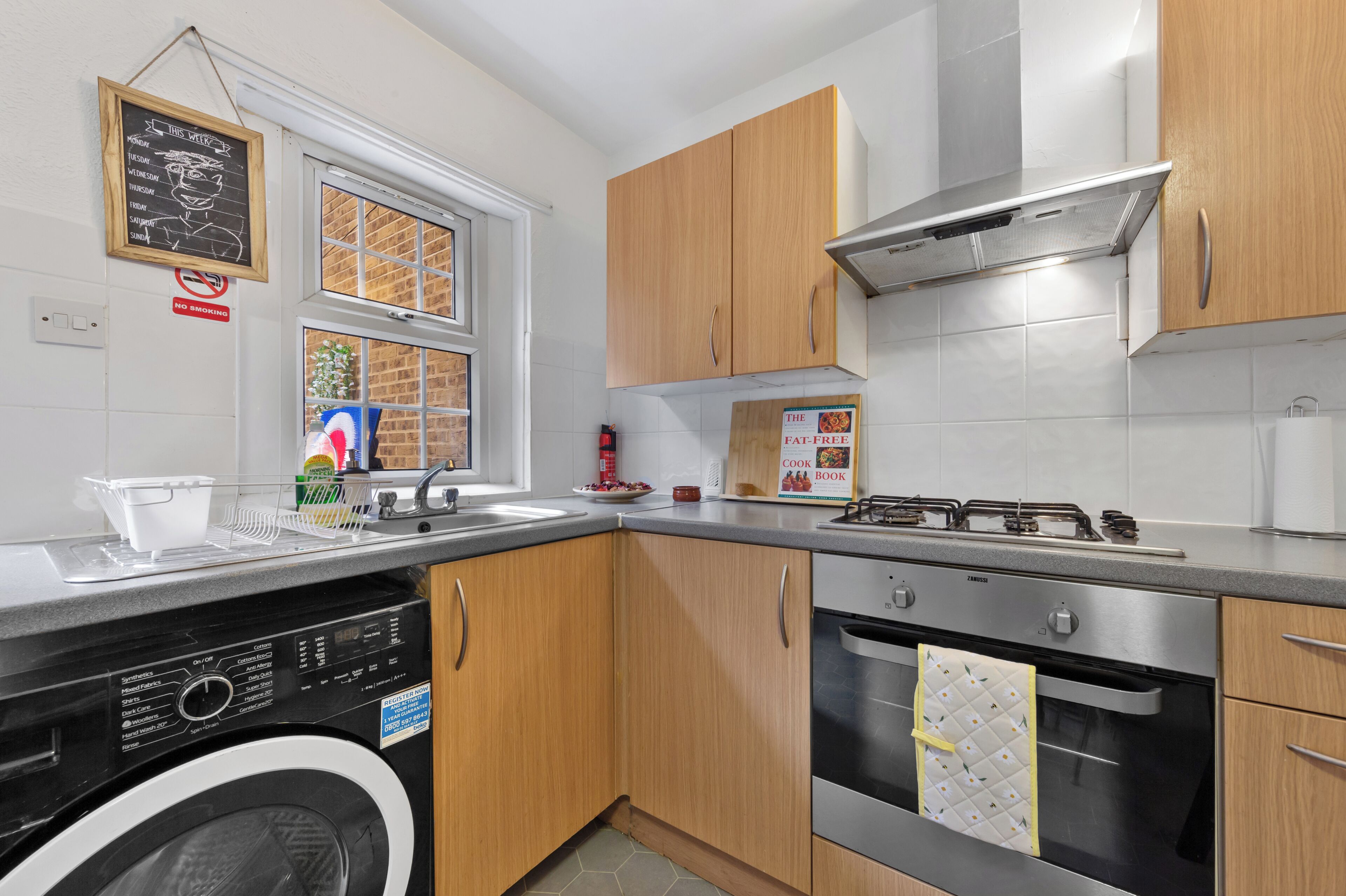 A compact kitchen with a dishwasher, stove, oven, and wooden cabinets.