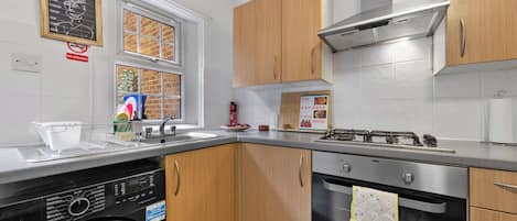 A compact kitchen with a dishwasher, stove, oven, and wooden cabinets.