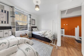 Une chambre à coucher avec un lit, une table de chevet, une fenêtre avec des rideaux et une vue sur un mur orange.