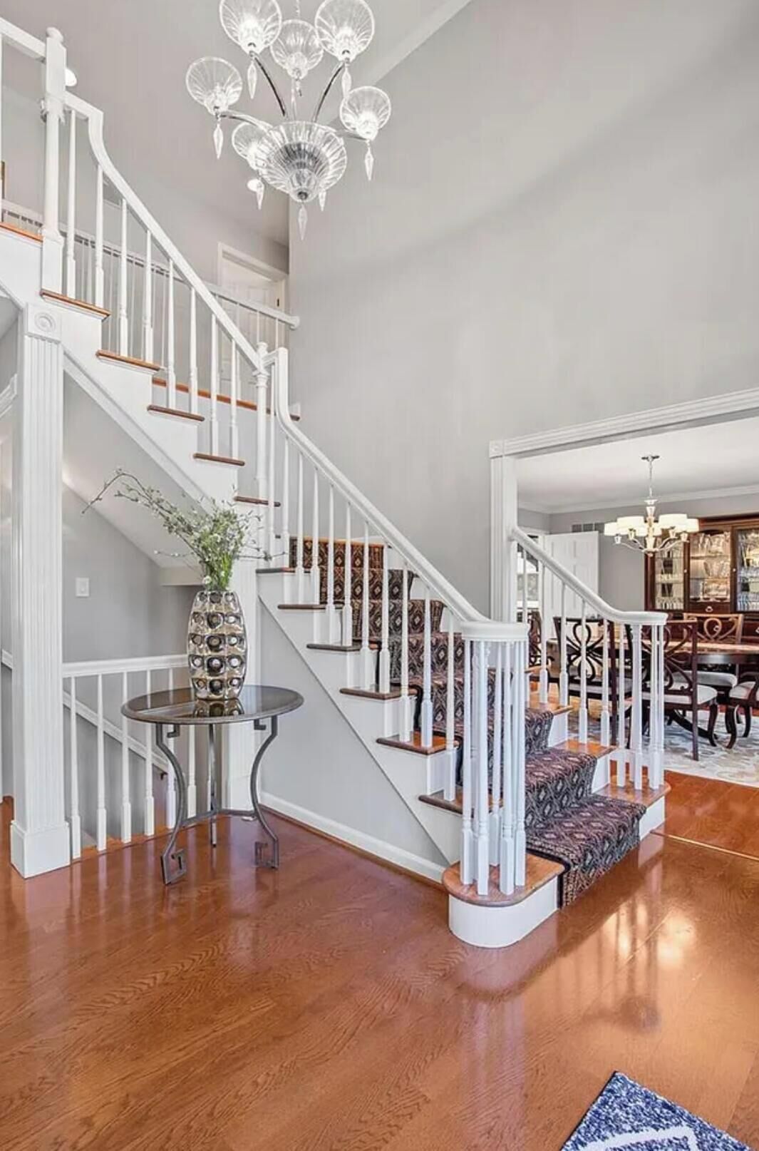 Una escalera con barandillas blancas y un candelabro.