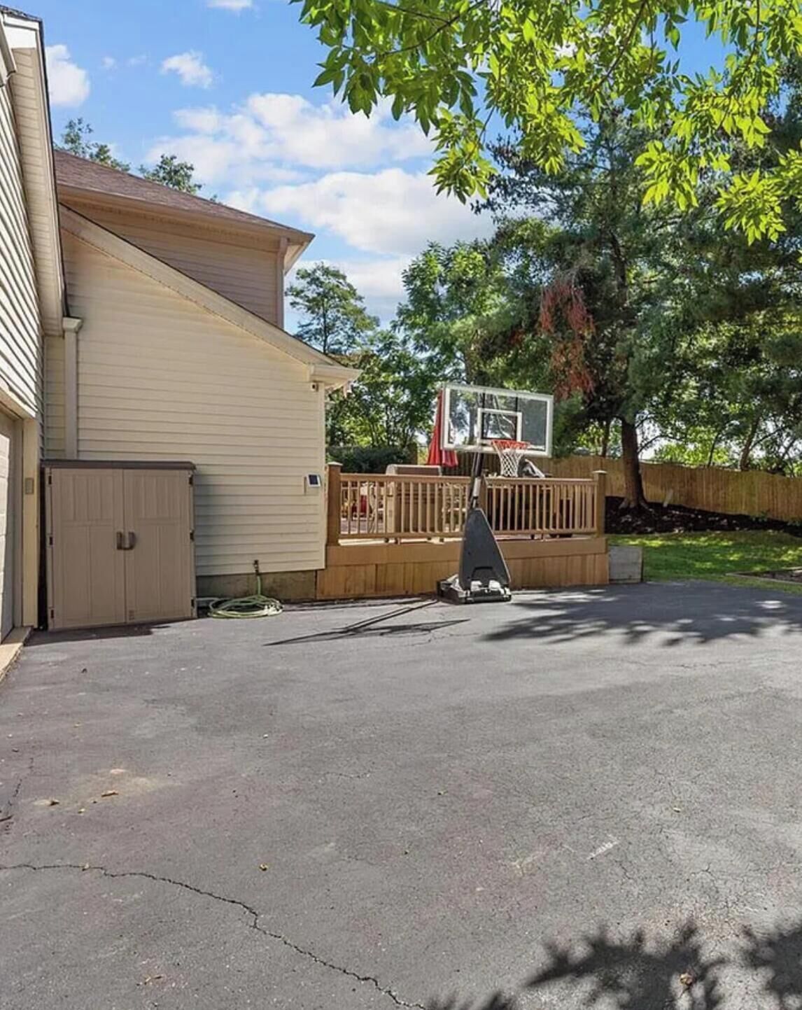 A residential property with a garage, a basketball hoop, and a tree.