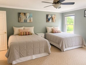 Ein Schlafzimmer mit zwei Betten, einem Deckenventilator und Kunstwerken an den Wänden.
