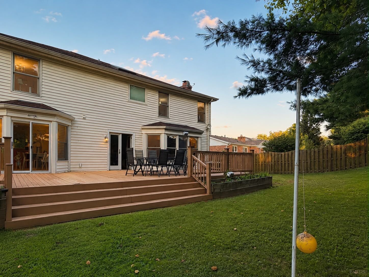 Une maison à deux étages avec un patio, une terrasse et une cour arrière clôturée.