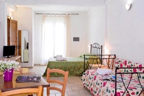 A hotel room with a bed, a desk with a computer, a chair, a sofa, and a window with curtains. - Borgo Primizia Room 2 B&B, Otranto, Italy (Otranto)