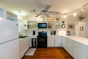 A kitchen with white cabinetry, a black stove, a ceiling fan, and a microwave. - Makin Time | Secluded Coastal Retreat | Easy Walk to Beach | Sleeps 8 | Dogs Welcome (Edisto Beach)