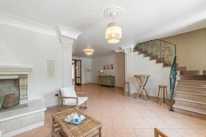 A spacious living room with a fireplace, a staircase, and a dining area with a table set for tea. - Casa di Adriana&Claudia, Porto Cesareo, Italy (Porto Cesareo)