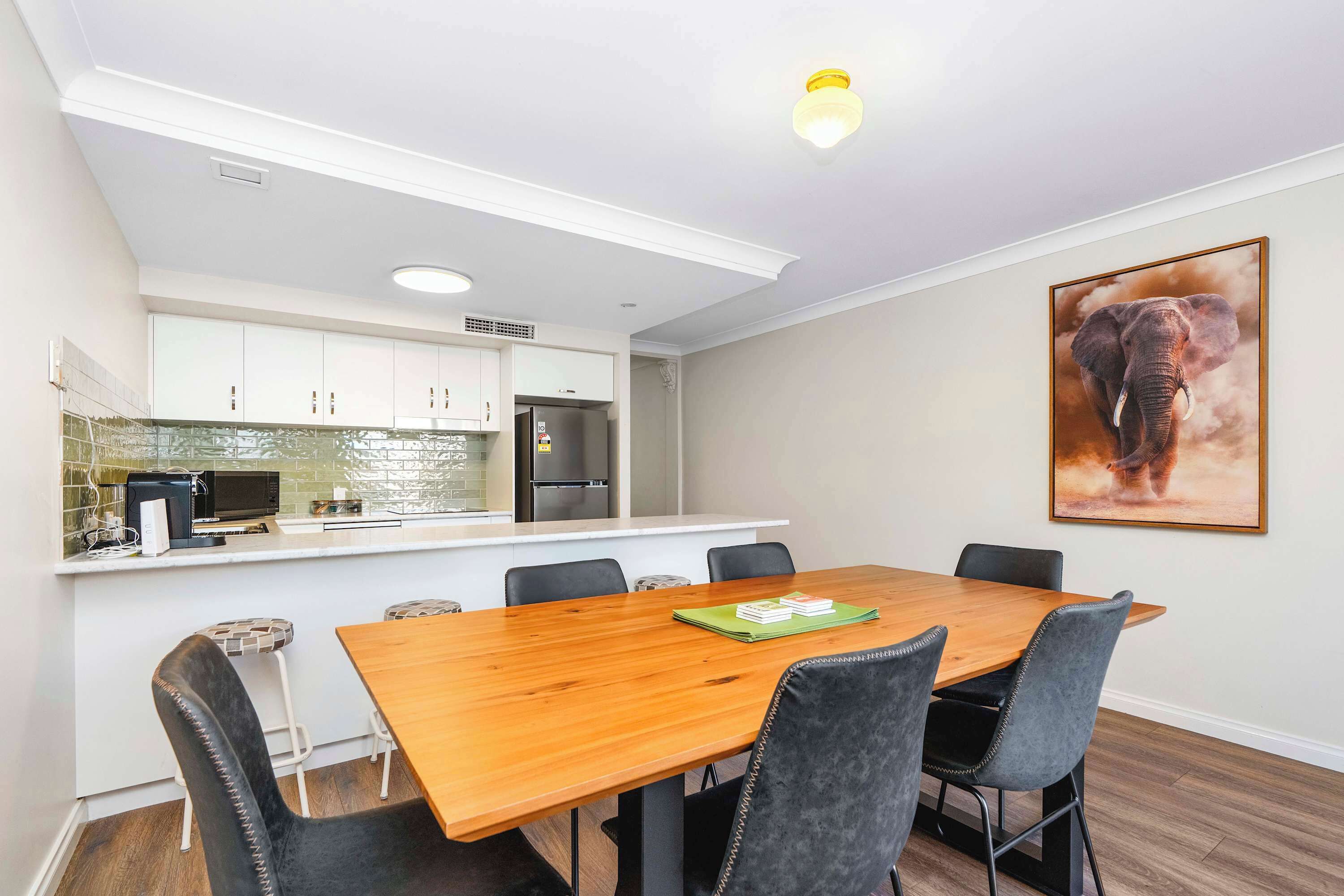 A modern kitchen with white cabinets, a stainless steel refrigerator, and a microwave.