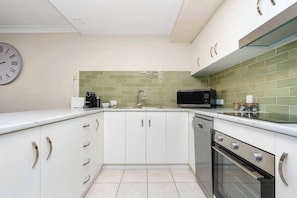 A modern kitchen with white cabinets, a microwave, a coffee maker, and a dishwasher.
