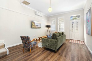 A living room with a sofa, chair, and a television on the wall.