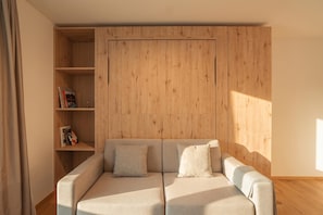 Uma sala de estar moderna com um sofá, uma estante de madeira e uma grande janela.