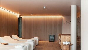 Ein moderner Wellnessraum mit Massagesesseln, einer Holzvertäfelung und einer Duschkabine aus Glas.