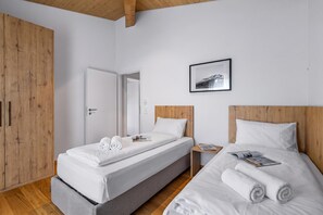 A hotel room with two single beds, a wooden wardrobe, a framed picture on the wall, and a wooden ceiling. - Residenza Castanea 308 San Bernardino Alpine Apartments, San Bernardino, Switzerland (San Bernardino)