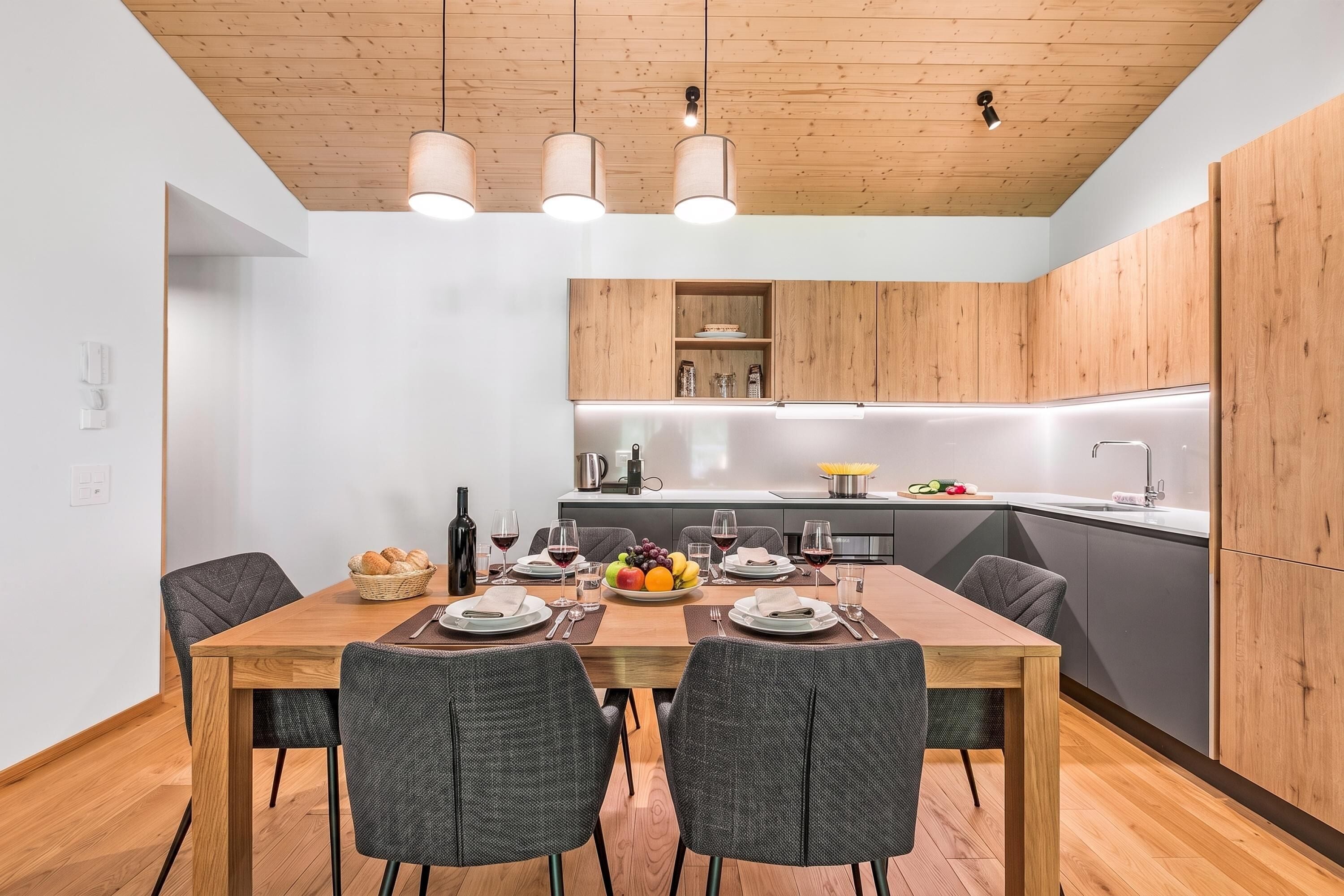 A modern kitchen with wooden cabinets, a dining table set for six, and a built-in oven.