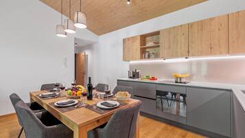 Una cocina moderna con armarios de madera, una mesa de comedor para cuatro personas y un horno empotrado.