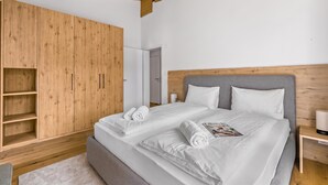 Ein modernes Schlafzimmer mit einem großen Bett, einem Holzschrank und einem grauen Kopfteil.