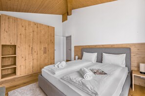 Ein modernes Schlafzimmer mit einem großen Bett, einem Holzschrank und einem grauen Kopfteil.