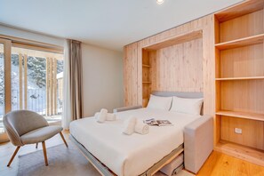 Une chambre moderne avec un grand lit, une chaise et des étagères en bois intégrées.
