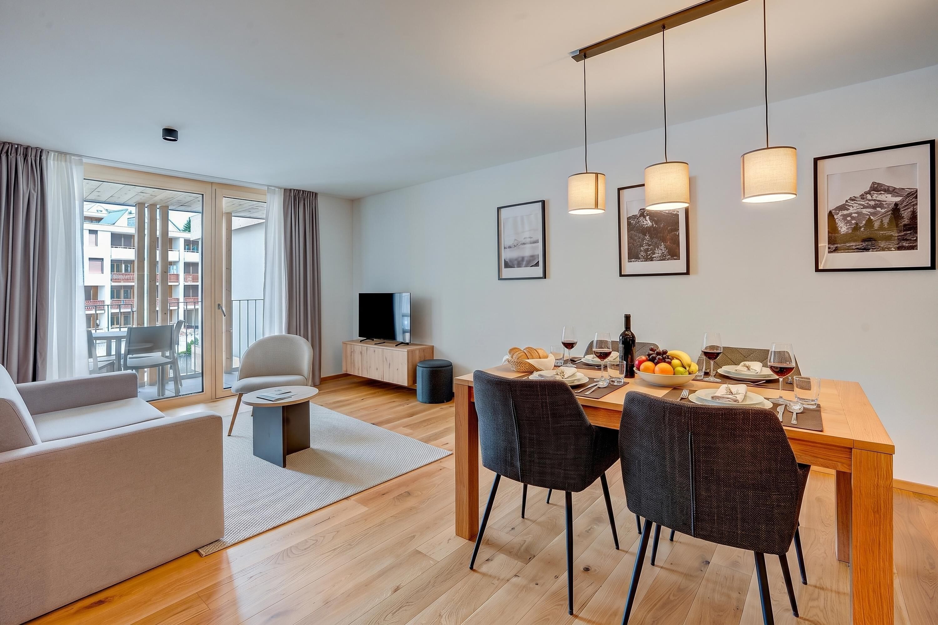 Ein stilvolles Wohnzimmer mit einer Couch, einem Esstisch für zwei Personen und einem Fernseher.