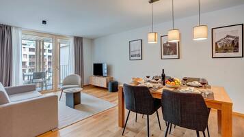 Una sala de estar moderna con un sofá, una mesa de comedor para dos personas y un televisor.