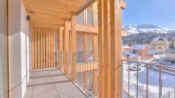 Ein Holzbalkon mit Blick auf einen verschneiten Berg und Gebäude.
