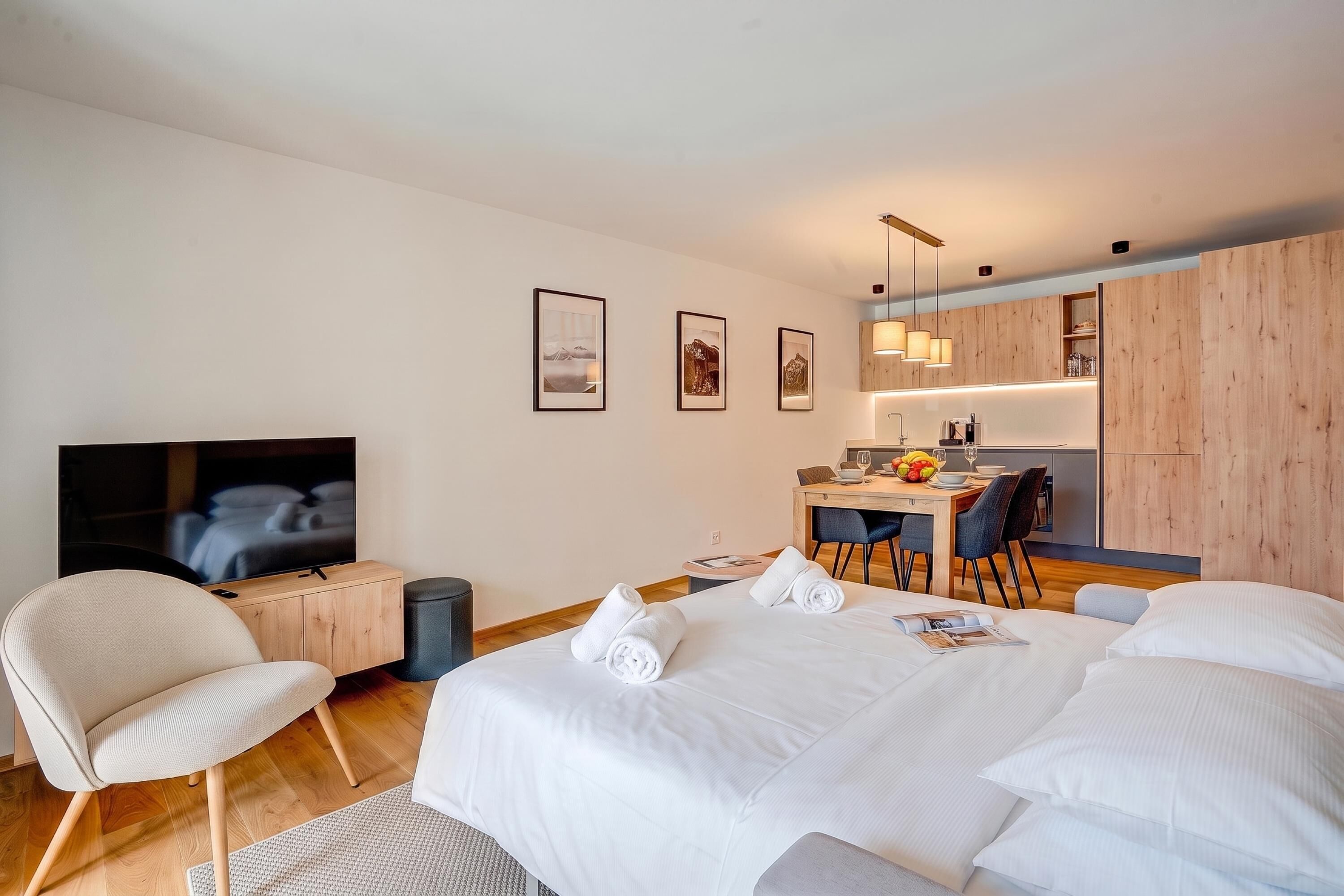 Habitació d'hotel moderna amb un llit gran, una televisió, escriptori amb cadira i zona de dinar.