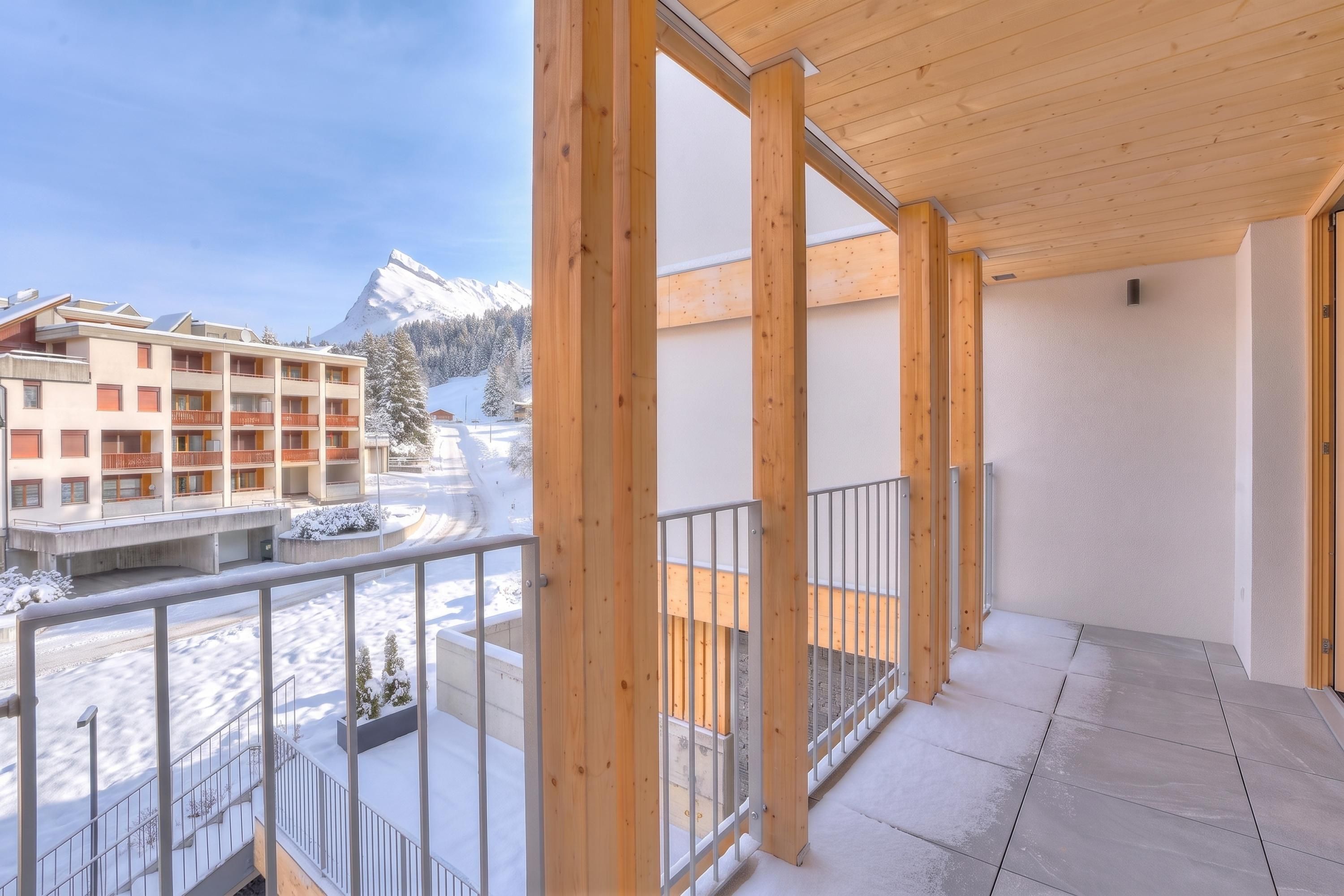 Ein Balkon mit Blick auf einen schneebedeckten Berg und Gebäude.