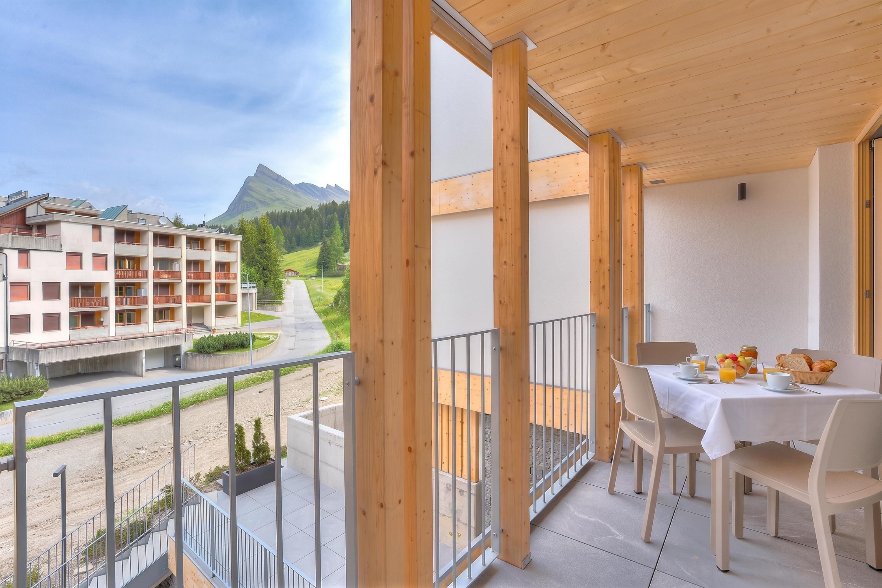 Ein Balkon mit gedecktem Tisch für das Frühstück, mit Blick auf eine Berglandschaft.