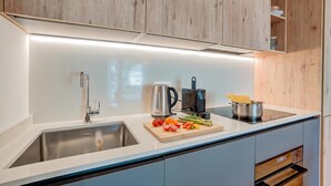 Eine moderne Küche mit Spüle aus Edelstahl, Wasserkocher, Toaster und frischem Gemüse auf der Arbeitsfläche.