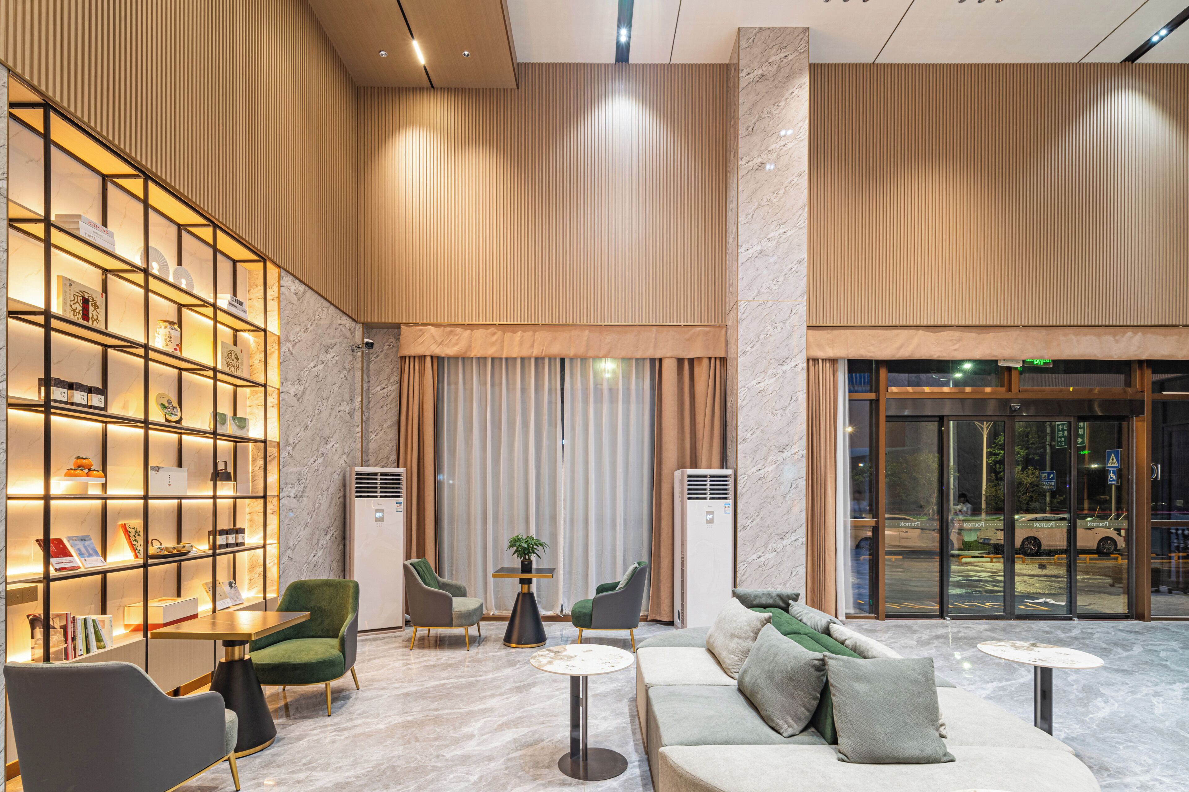 Een moderne lobby met een zithoek, een boekenkast en een receptiebalie.