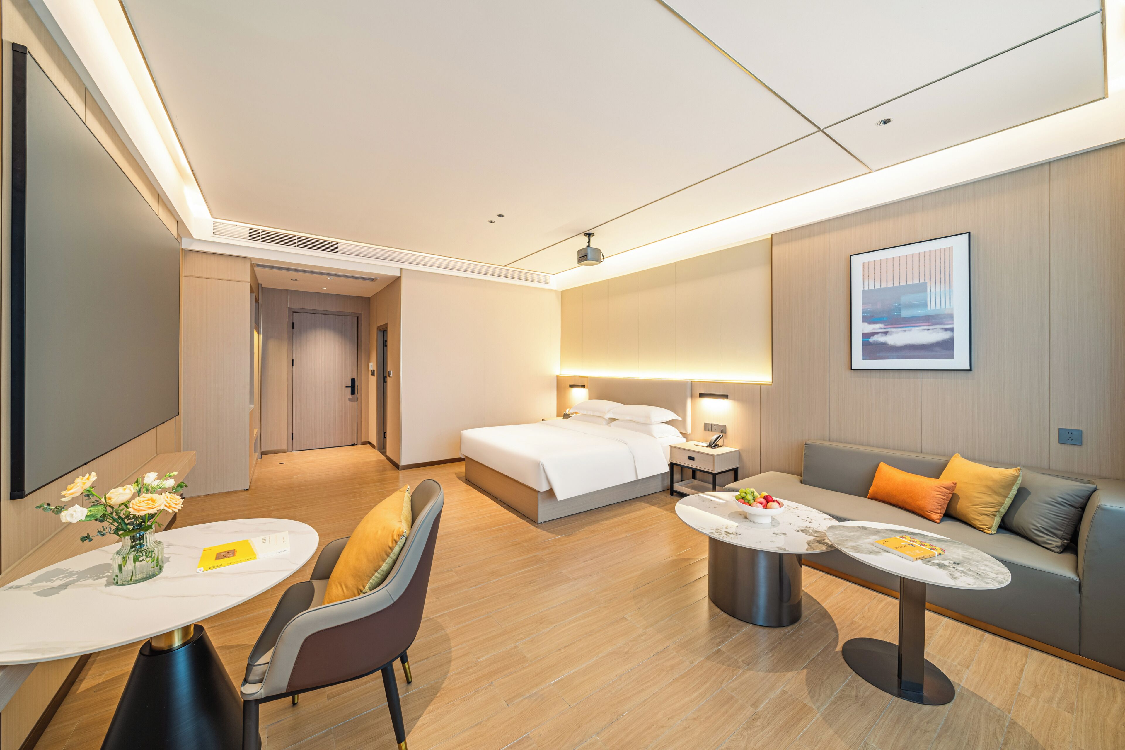 Een moderne hotelkamer met een bed, een slaapbank, een eettafel en een televisie.