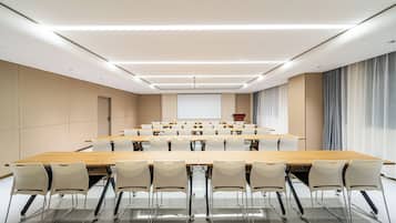 A conference room with a long table, chairs, a projector screen, and a podium.