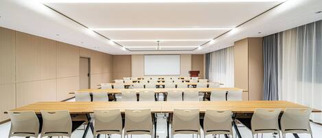 A conference room with a long table, chairs, a projector screen, and a podium.