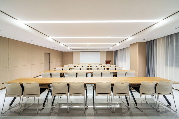 A conference room with a long table, chairs, a projector screen, and a podium.